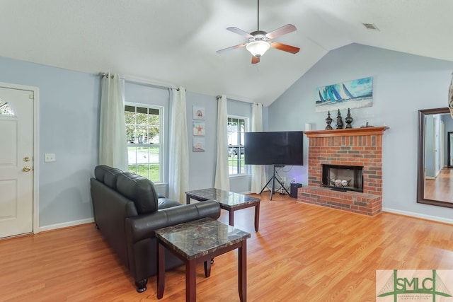 living room featuring a brick fireplace, light wood-type flooring, vaulted ceiling, and ceiling fan