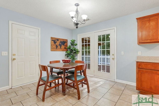 dining area with light tile patterned flooring, a textured ceiling, and an inviting chandelier