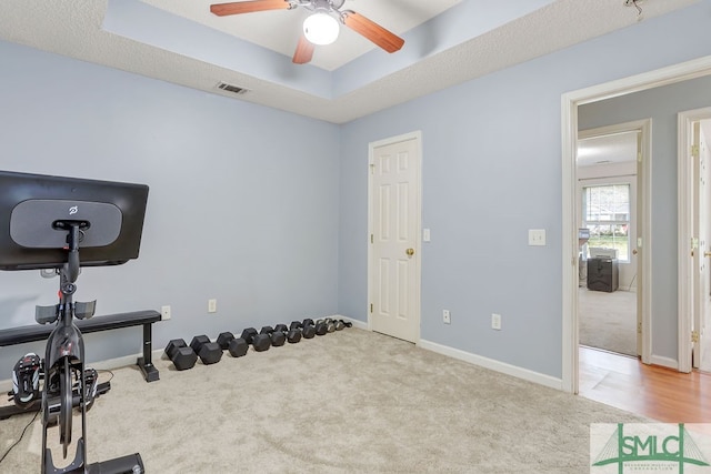 workout area featuring a textured ceiling, ceiling fan, and light carpet