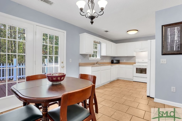 kitchen featuring pendant lighting, a healthy amount of sunlight, white cabinets, and white appliances