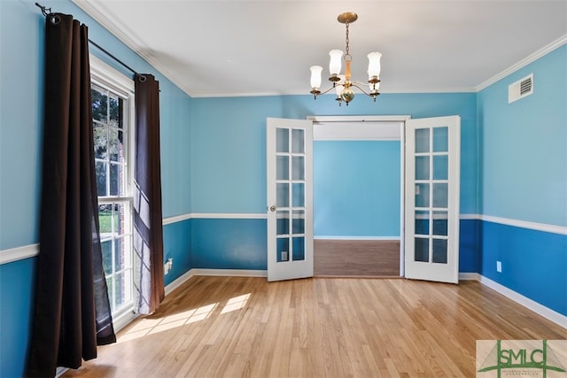 unfurnished dining area with ornamental molding, french doors, a chandelier, and light hardwood / wood-style flooring