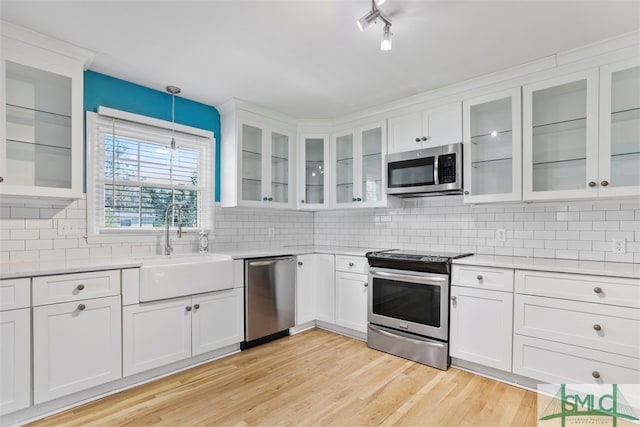 kitchen featuring light hardwood / wood-style floors, pendant lighting, stainless steel appliances, backsplash, and white cabinets