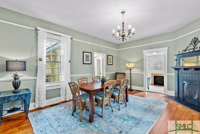 dining space featuring a notable chandelier, a tile fireplace, and hardwood / wood-style floors