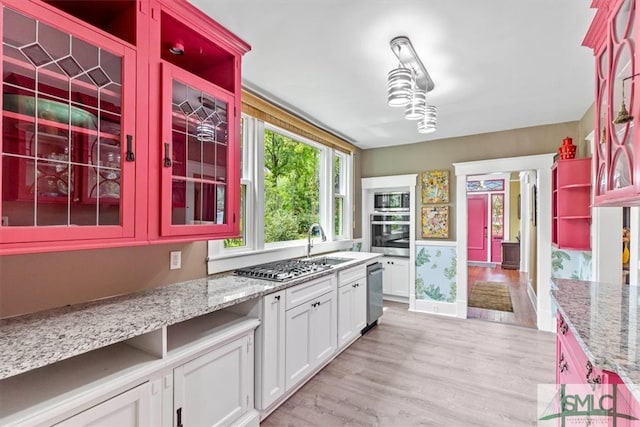 kitchen with light wood-type flooring, white cabinetry, appliances with stainless steel finishes, and sink