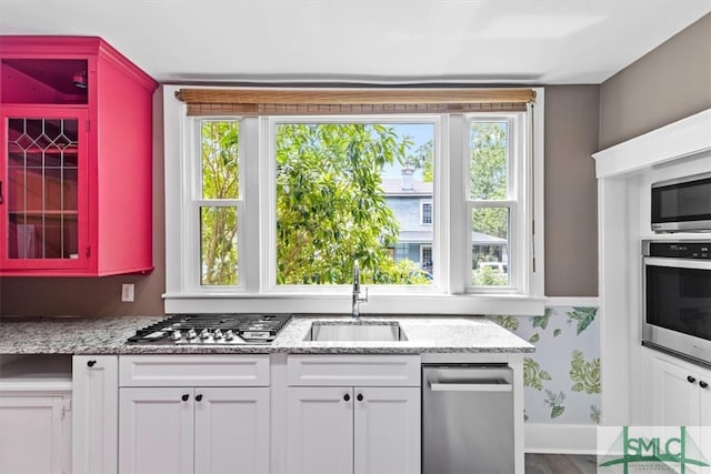 kitchen with a wealth of natural light, white cabinetry, and appliances with stainless steel finishes