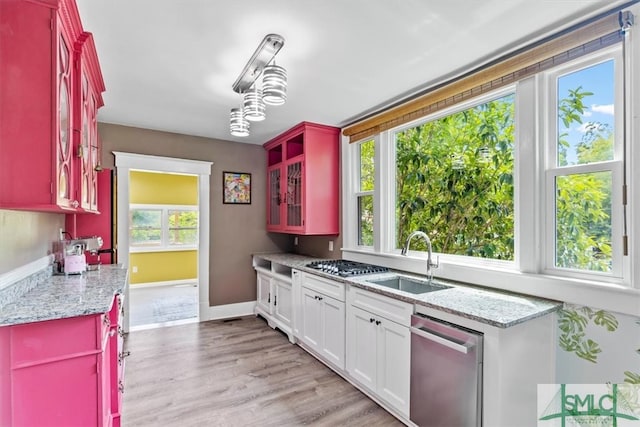 kitchen with sink, white cabinets, light hardwood / wood-style flooring, appliances with stainless steel finishes, and light stone countertops