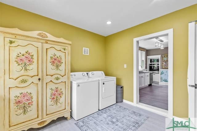 laundry area with light hardwood / wood-style floors, sink, and washing machine and dryer