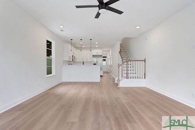 unfurnished living room featuring ceiling fan and light hardwood / wood-style flooring