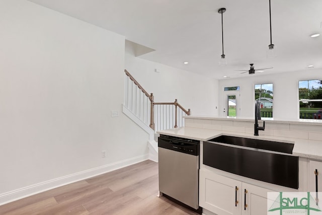 kitchen featuring light wood-type flooring, decorative light fixtures, sink, dishwasher, and white cabinetry