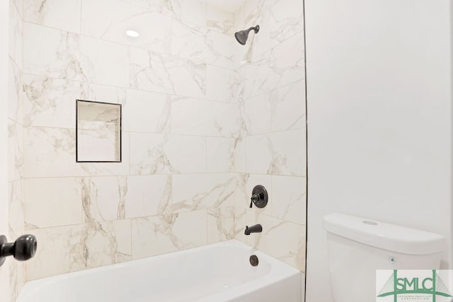 bathroom with toilet and tiled shower / bath