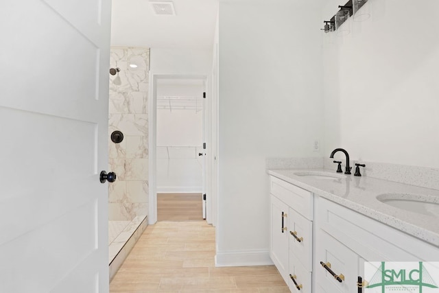 bathroom with vanity, a tile shower, and hardwood / wood-style flooring