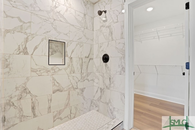 bathroom featuring hardwood / wood-style flooring and a tile shower