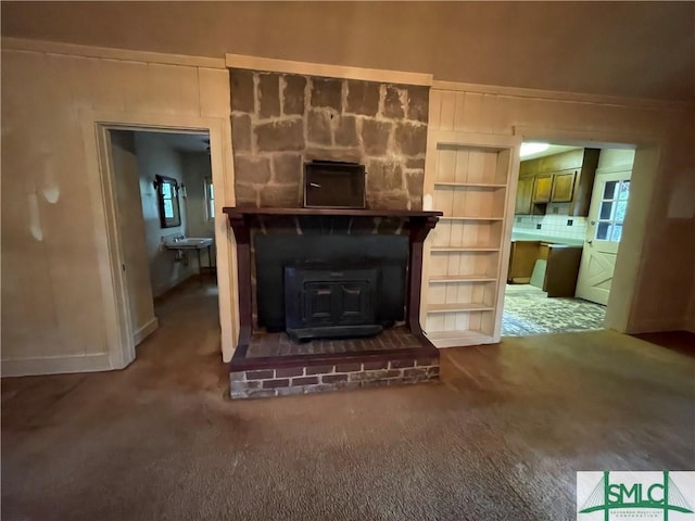 unfurnished living room with a wood stove, carpet floors, and sink