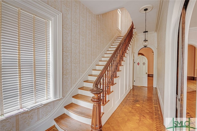 staircase featuring parquet flooring and crown molding