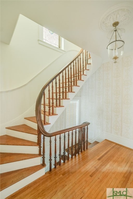 stairway featuring a notable chandelier and wood-type flooring