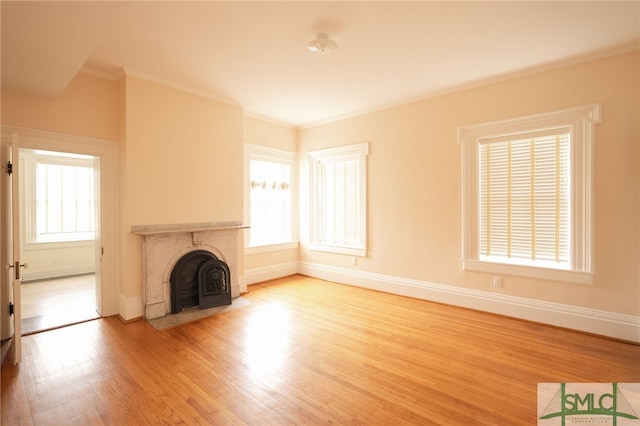 unfurnished living room with a wealth of natural light, a premium fireplace, hardwood / wood-style flooring, and crown molding