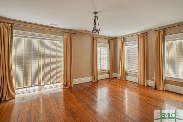 empty room with wood-type flooring and a notable chandelier