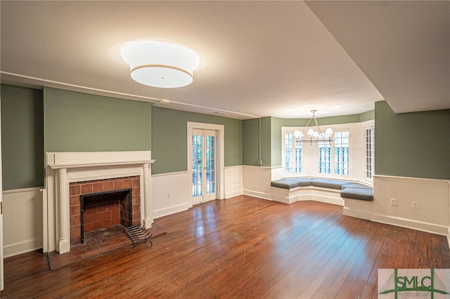 unfurnished living room with a notable chandelier, a tile fireplace, and hardwood / wood-style flooring