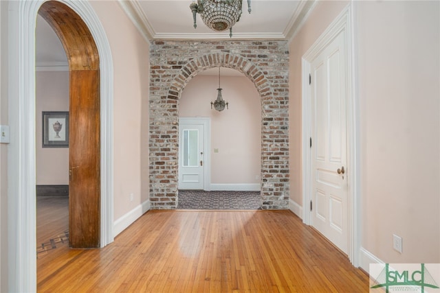 entrance foyer featuring ornamental molding, light hardwood / wood-style flooring, and a notable chandelier