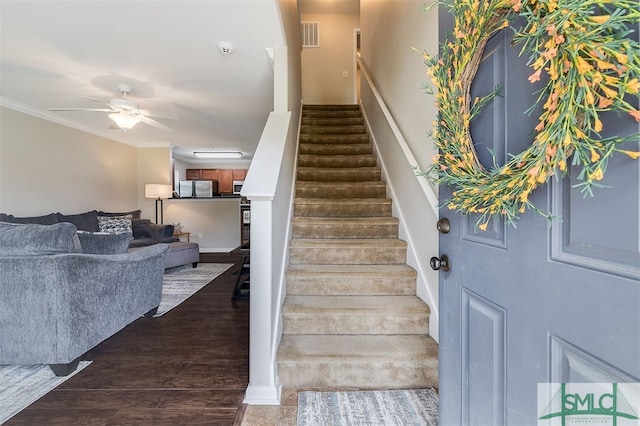 stairway with ornamental molding, wood-type flooring, and ceiling fan