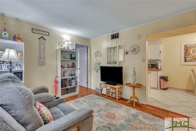 living room with light wood-type flooring, a textured ceiling, and crown molding