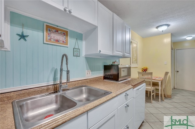 kitchen with a textured ceiling, sink, white cabinetry, light tile patterned floors, and white dishwasher