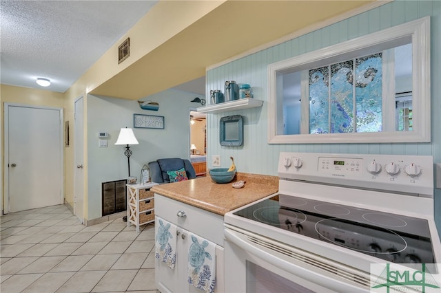 kitchen featuring white cabinets, a textured ceiling, light tile patterned floors, and white range with electric stovetop