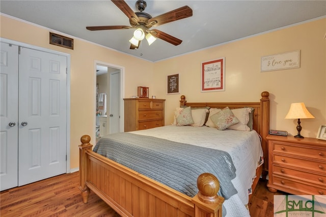 bedroom featuring ensuite bath, ceiling fan, a closet, and hardwood / wood-style flooring