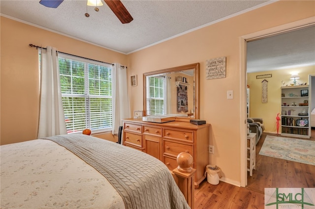 bedroom with ornamental molding, light wood-type flooring, ceiling fan, and a textured ceiling