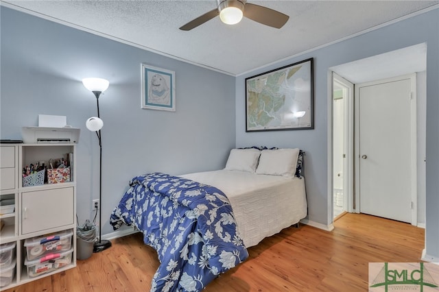 bedroom with ceiling fan, hardwood / wood-style flooring, crown molding, and a textured ceiling