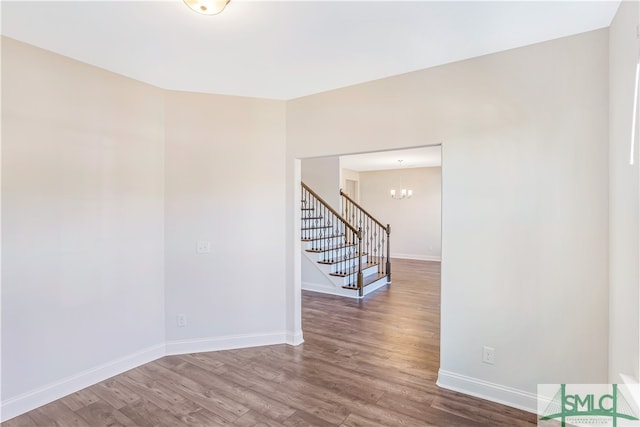 empty room with hardwood / wood-style flooring and an inviting chandelier