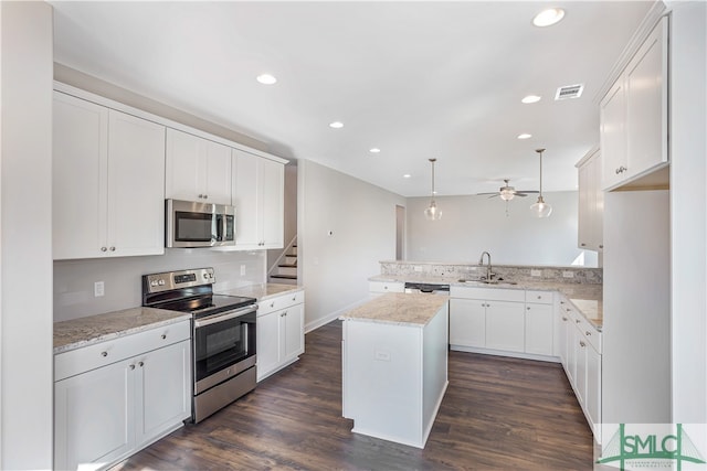 kitchen with pendant lighting, a kitchen island, stainless steel appliances, and dark hardwood / wood-style floors