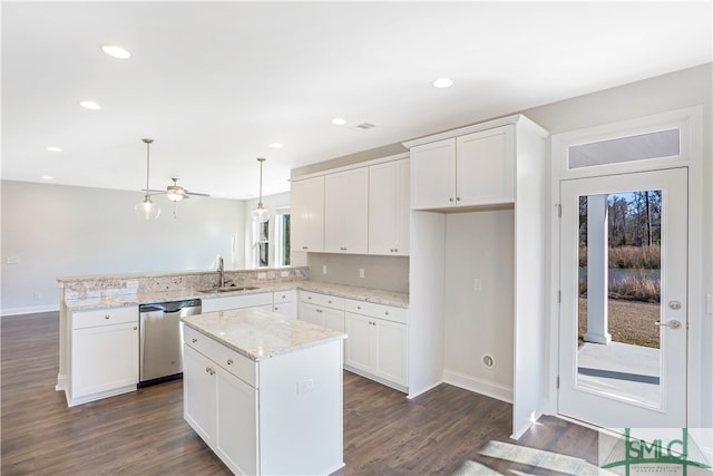 kitchen featuring dishwasher, a kitchen island, white cabinetry, and decorative light fixtures