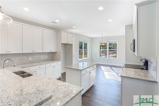 kitchen with hanging light fixtures, a kitchen island, black range, and sink