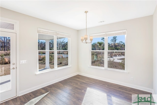 unfurnished dining area featuring a notable chandelier and dark hardwood / wood-style floors