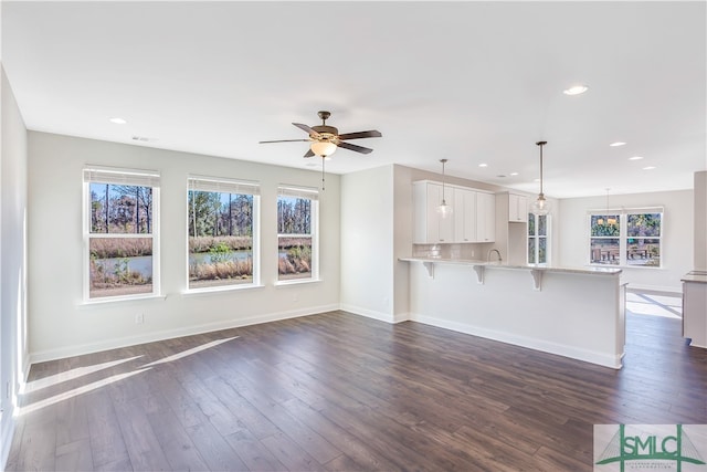 unfurnished living room with ceiling fan, sink, and dark hardwood / wood-style floors