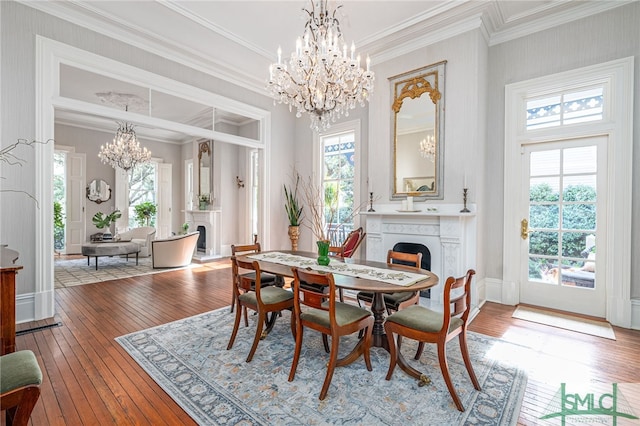 dining room with ornamental molding, an inviting chandelier, plenty of natural light, and light hardwood / wood-style floors