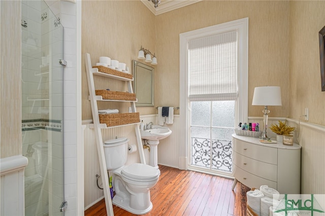 bathroom with ornamental molding, toilet, a shower with door, and hardwood / wood-style floors