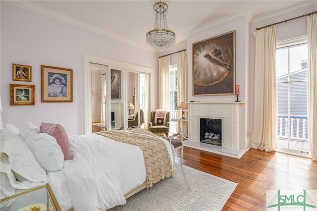 bedroom featuring multiple windows, access to exterior, hardwood / wood-style floors, and crown molding