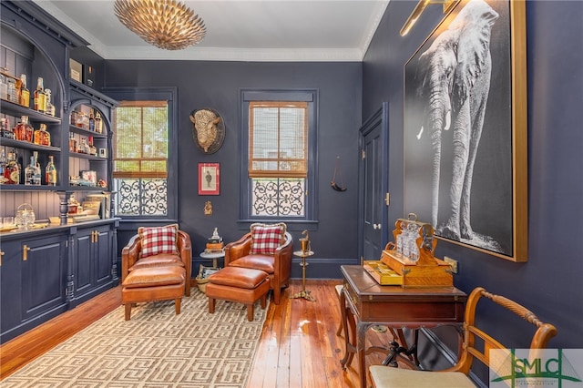 living area featuring a healthy amount of sunlight, ornamental molding, and light hardwood / wood-style flooring