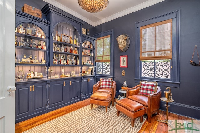 sitting room featuring bar area, light hardwood / wood-style flooring, and crown molding