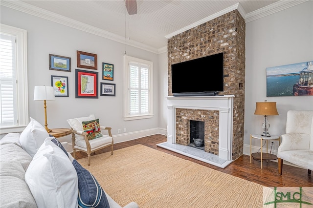 bedroom featuring a brick fireplace, ornamental molding, hardwood / wood-style floors, and ceiling fan