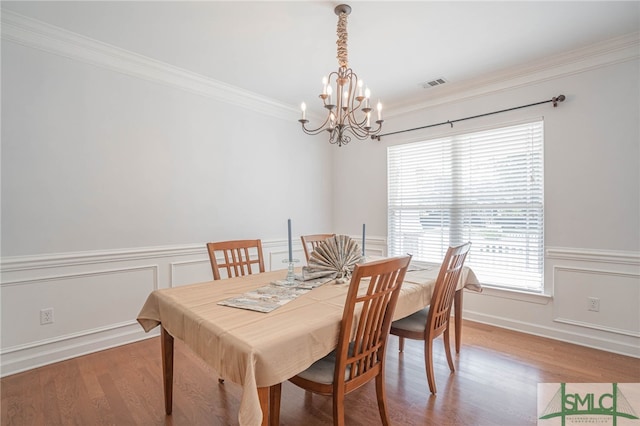 dining room with an inviting chandelier, hardwood / wood-style floors, and crown molding