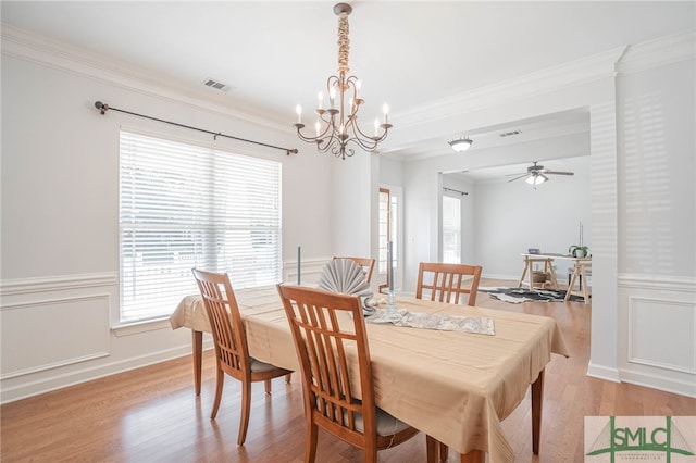 dining area featuring light wood-type flooring, ceiling fan with notable chandelier, and ornamental molding