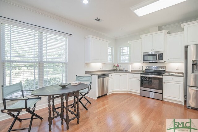 kitchen featuring stainless steel appliances, white cabinetry, and plenty of natural light