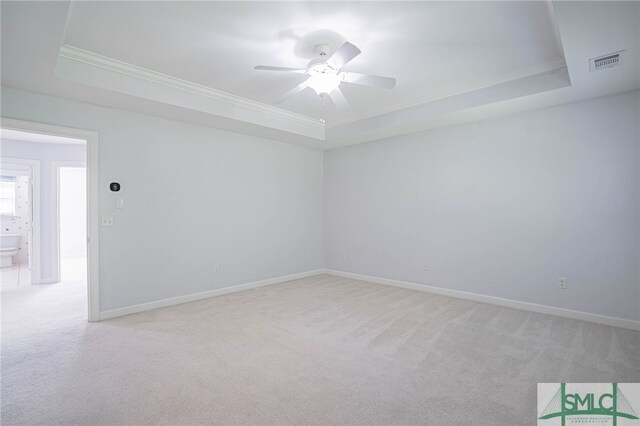 unfurnished room featuring ceiling fan, light colored carpet, and a raised ceiling