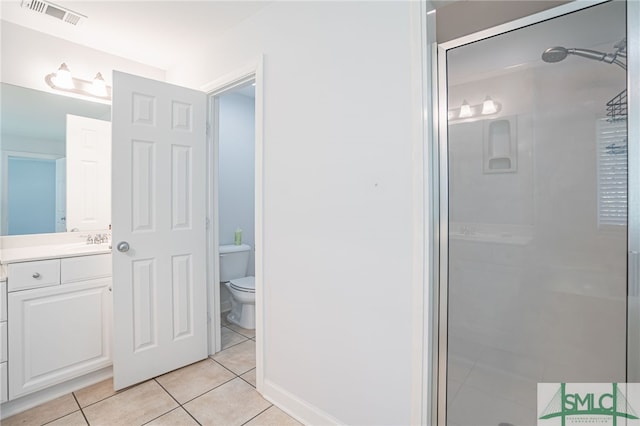 bathroom featuring tile patterned floors, a shower with door, vanity, and toilet