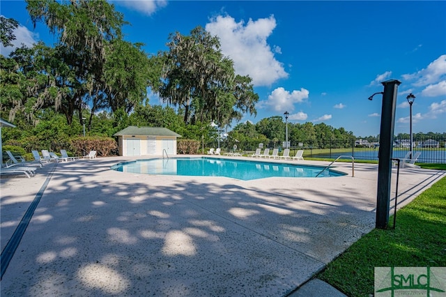 view of swimming pool with a patio and an outbuilding