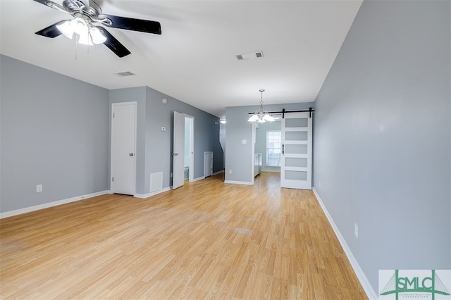 unfurnished living room with light wood-type flooring, ceiling fan, and a barn door