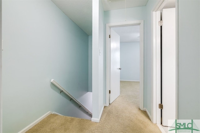 corridor featuring light colored carpet and a textured ceiling